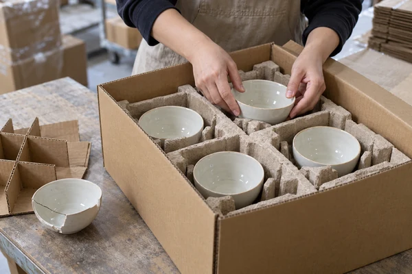 Packing worker checking fitted protective inserts around replacement ceramic bowls